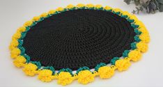 a crocheted black and yellow placemat with green, yellow and white trim