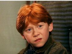 a young boy with red hair sitting in front of a mirror looking at the camera