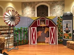 an indoor stage set with hay bales and fake animals on the floor in front of it