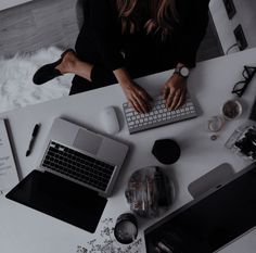 a woman sitting at a desk typing on a computer keyboard with other office supplies around her