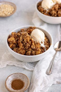 two bowls filled with granola and ice cream on top of a white table cloth