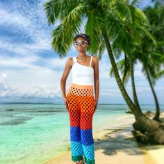 a woman standing on top of a sandy beach next to palm trees and the ocean