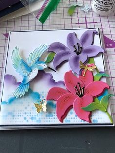 a card with flowers cut out of paper on top of a piece of crafting paper