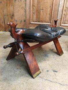 a wooden bench with black leather seat and foot rest in front of a wood paneled wall