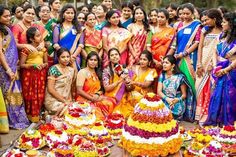 a group of women standing in front of a table with cakes and flowers on it