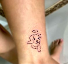 a small tattoo on the leg of a woman with a dog and angel halo above her head