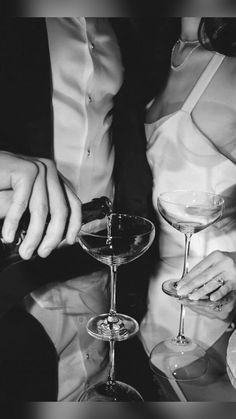 a man and woman holding wine glasses in front of each other on a table at a party