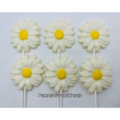 four white and yellow flowers are on top of each other in the shape of lollipops