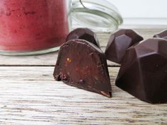 three pieces of chocolate next to a jar of red liquid