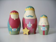 three wooden nesting dolls sitting next to each other on a white surface with a star in front of them