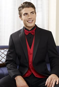 a man in a tuxedo is sitting on a couch and smiling at the camera