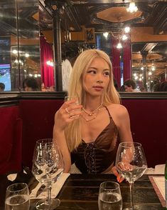 a woman sitting at a table with wine glasses