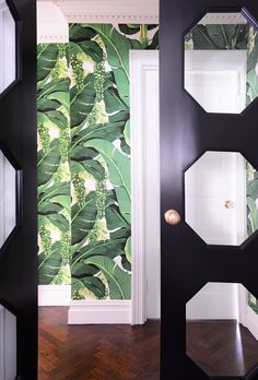 an open door leading to a room with green wallpaper on the walls and wooden floors