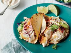 two fish tacos on a blue plate with lime wedges