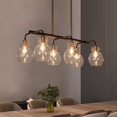 a chandelier with five clear glass globes hanging over a dining room table