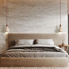 a bed with two lamps hanging above it in a room that has concrete walls and flooring