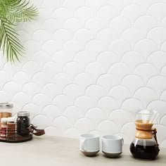 three coffee cups sitting on top of a counter next to a potted palm tree