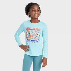 The Tune Squad Slam Dunk Long-Sleeve Graphic T-Shirt is perfect for any fan of the sports comedy series and film. Your child will look cute and feel comfortable all day in this pullover jersey tee, thanks to its soft fabric construction. A cheerful illustration of the Tune Squad characters in their jerseys, along with the glitter-detailed text "Slam Dunk," accents the front of this long-sleeve T-shirt for a fun look. It's finished in a light aqua green shade that makes a refreshing pairing with Sporty Long Sleeve Tops With Character Print, Sporty Cotton Tops With Cartoon Print, Sporty Tops With Character Print For Sports, Graphic Tee With Character Print And Long Sleeves, Blue Character Print Fan Apparel Tops, Blue Character Print Tops For Fans, Blue Tops With Character Print For Fans, Fun Cotton Sports Tops, Blue Fan Apparel Tops With Character Print