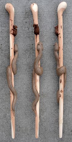 three carved wooden sticks with snakes on them