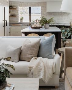 a living room filled with furniture next to a kitchen