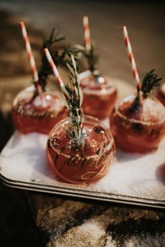 four glasses with candy canes in them sitting on a tray next to each other