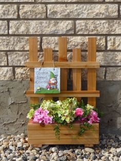 a wooden planter filled with flowers next to a brick wall