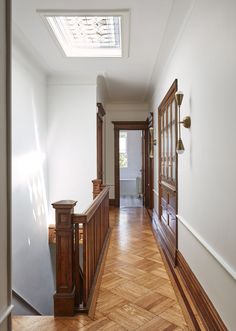 an empty hallway with wood floors and skylight