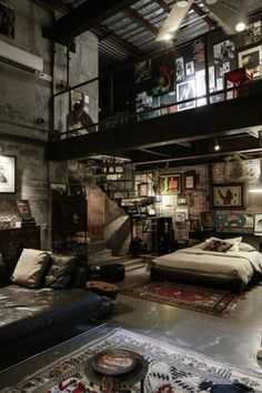 an industrial loft with exposed ceilings and lots of furniture in the room, including a bed