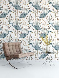 a chair and table in front of a wallpaper with blue birds on the background