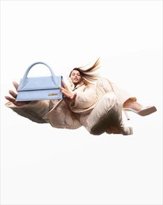 a woman flying through the air with a blue handbag on her back and legs