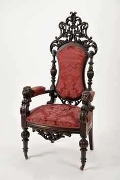 an ornately carved chair with red upholstered seat and arm rests against a white background