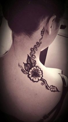 the back of a woman's neck with a flower tattoo on it