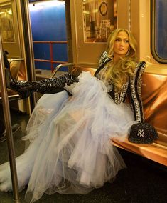 a woman in a dress and hat sitting on a train