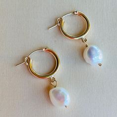 Lanai Pearl and Small Hoop Earrings. Inspired by the simple beauty of pearls, this earring showcases an asymmetrical pearl paired with a shinny golden hoop, creating a classic and feminine earring perfect for day- and night- wear.    14Kt Gold Filled hoop   White Potato Peal Pearl  Approx. 1.5" long  Made in USA Pearl White Hoop Earrings With Pearl Drop, Modern Hoop Earrings With Pearl Charm, Minimalist Small Hoop Pearl Drop Earrings, Small Hoop Pearl Chain Earrings, Minimalist Pearl Charm Hoop Earrings, Minimalist Hoop Earrings With Pearl Chain, Hoop Pearl Earrings With Pearl Pendant, Small Hoop Pearl Drop Earrings, Small Hoop Pearl Earrings