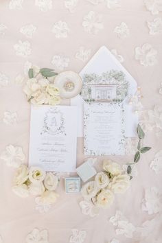 the wedding stationery is laid out with flowers and rings on it's side