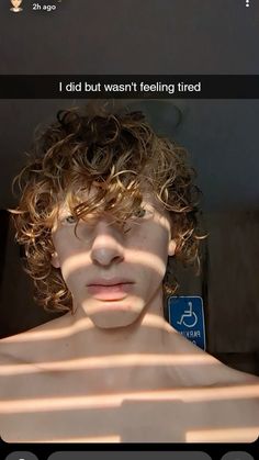 a man with curly hair is looking at the camera and has his shadow cast on him