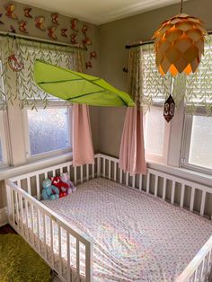 a baby's crib with a green umbrella hanging from the ceiling above it