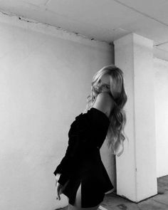 black and white photograph of a woman leaning against a wall