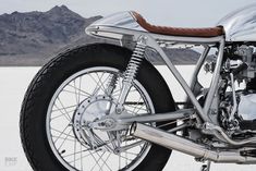 a motorcycle parked in the desert with mountains in the background