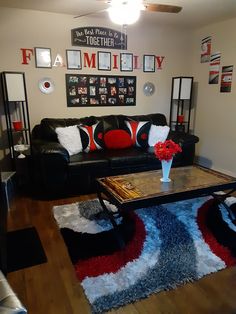 a living room with black leather couches and colorful rugs on the wooden floor