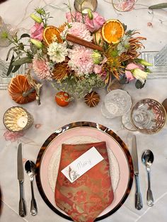 the table is set with an orange and pink floral centerpiece, silverware, and napkins