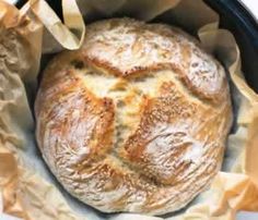 a loaf of bread sitting inside of a black crock pot on top of a table