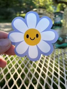 a person holding up a flower with a smiley face on it