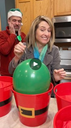 two people in santa hats are sitting at a table with buckets and toothbrushes