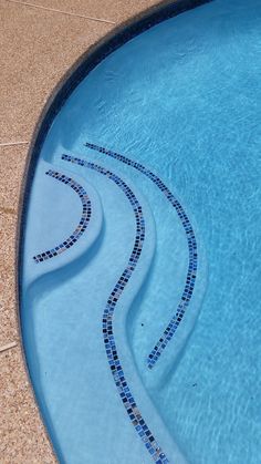 an empty swimming pool with blue tiles on the edge and water running down it's sides