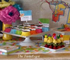 a table topped with cupcakes covered in frosting next to other desserts