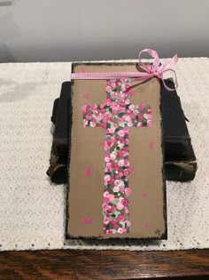 a cross painted on top of an old book with pink and green flowers tied to it