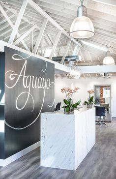 an office with white marble counter tops and black walls, along with wooden flooring