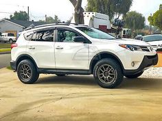 a white toyota rav parked on the side of a road next to a tree