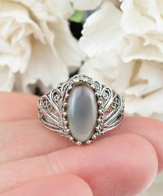 This stunning cocktail ring is crafted with high-quality 925 sterling silver and features an intricate filigree art design. The centerpiece of the ring is a beautiful gray moonstone gemstone that is set in a unique angel wings design, giving the ring a truly one-of-a-kind look. Gray moonstone is a popular gemstone known for its iridescent sheen and believed to have calming and balancing properties. It's also said to promote inner strength and intuition. This cocktail ring is perfect for special Angel Wings Design, The Ring Face, Wings Design, Sterling Silver Filigree, Filigree Ring, Silver Filigree, Cocktail Rings, Moonstone, Art Design